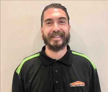 Male with dark hair, beard, wearing a green striped shirt on shoulders with SERVPRO logo.