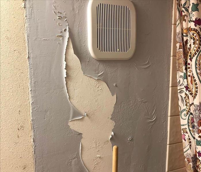 Grey paint falling off wall due to a water leak.